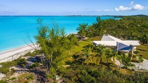 Une propriété située en bord de mer, comprenant une grande maison, une piscine et une vue sur l’océan.