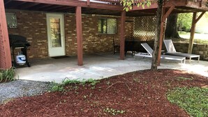 Un’area patio coperta con muro in mattoni, barbecue e poltrone relax.