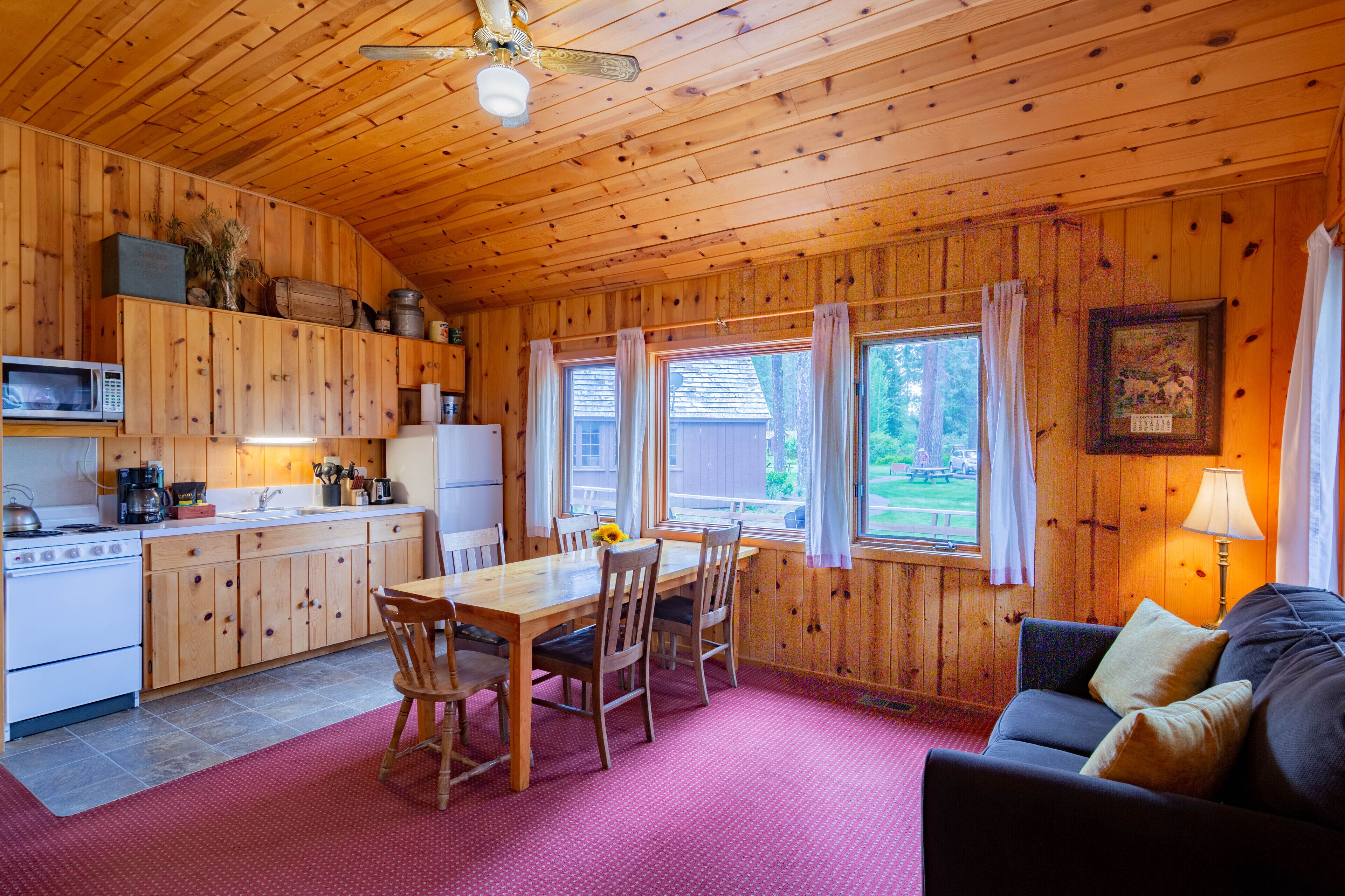 Une cabane en bois comprenant une cuisine, un coin repas et un salon avec un canapé.