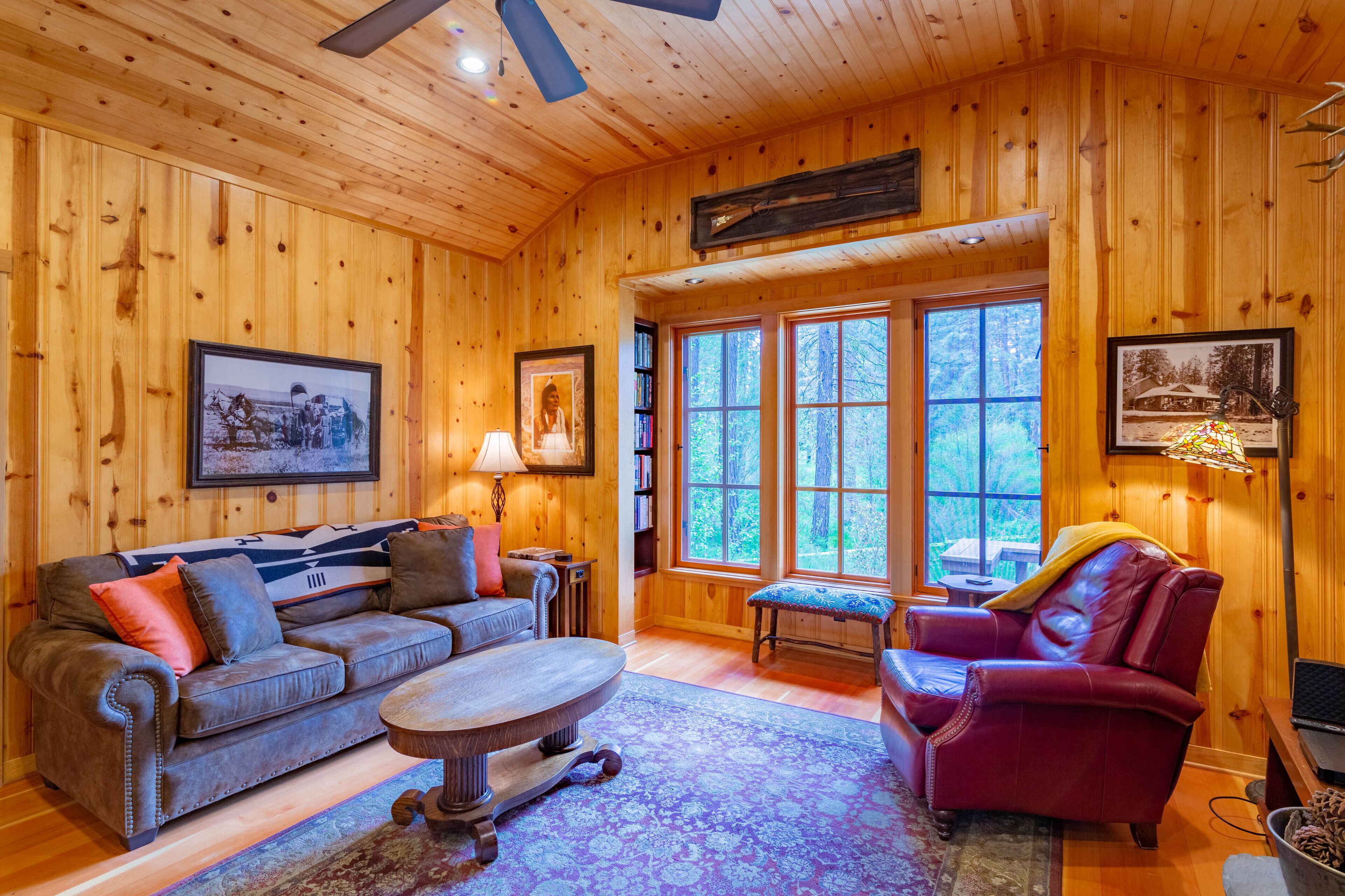 A wooden-paneled room with a sofa, armchair, and a round table.