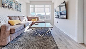 Ett modernt vardagsrum med en soffa, ett soffbord och ett stort fönster med utsikt över stadsbilden.