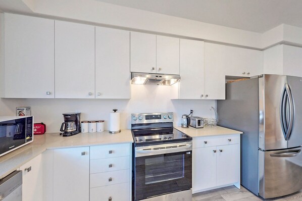 A modern kitchen with white cabinets, stainless steel appliances, and a built-in oven.