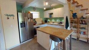 Una cucina funzionale con un tavolo di legno e due sedie, un frigorifero e uno scaffale con diversi oggetti.