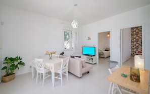 A modern living room with a dining area, a television, and a cozy seating arrangement.