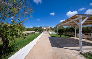 A pathway leading to a building with a covered area on the right.
