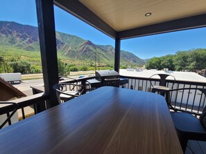 Un espace extérieur aménagé pour prendre les repas, offrant une vue sur les montagnes et une route.