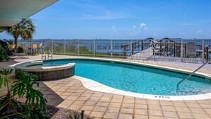 A swimming pool with a view of the ocean, surrounded by a fence and palm trees. - Quiet and relaxing with three balconies. Located on the Santa Rosa Sound. (Navarre)