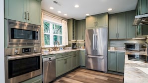 A modern kitchen with green cabinets, stainless steel appliances, and a large window. - 2 BR + Loft/2BA Tarpon Pond Cottage! Great Views! 1 Dog Friendly! (Seabrook Island)