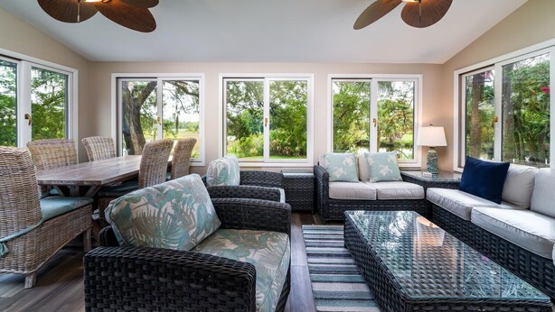 A sunroom with wicker furniture, large windows, and ceiling fans. - 2 BR + Loft/2BA Tarpon Pond Cottage! Great Views! 1 Dog Friendly! (Seabrook Island)