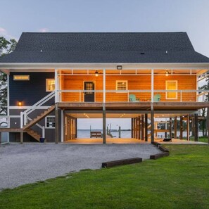 Een herenhuis aan het water met een overdekt terras en een trap naar de bovenverdieping.