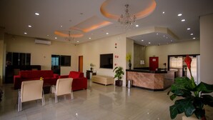A spacious lobby with a reception desk, red sofas, and a large potted plant. - Hotel Atrium Express (Parauapebas)