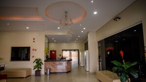 A hotel lobby with a reception desk, seating area, and a large plant. - Hotel Atrium Express (Parauapebas)
