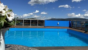 A swimming pool with a clear blue sky and clouds in the background.
