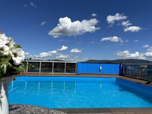 A swimming pool with a clear blue sky and clouds in the background.