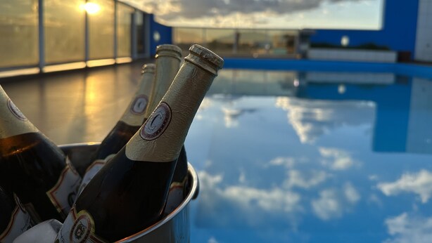 A poolside view with bottles in a bucket, a clear sky, and a building in the background. - Hotel Atrium Express (Parauapebas)