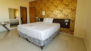 A hotel room with a large bed, a bathroom with a mirror, and a patterned wall.