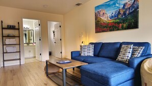 Una sala de estar moderna con un sofá azul, una mesa de centro y un cuadro de un paisaje montañoso.