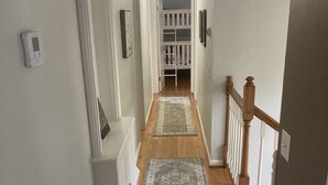 A narrow hallway with wooden floors, white walls, and a white railing on the right. - Visit Monticello, Wineries, UVA & More (Troy)