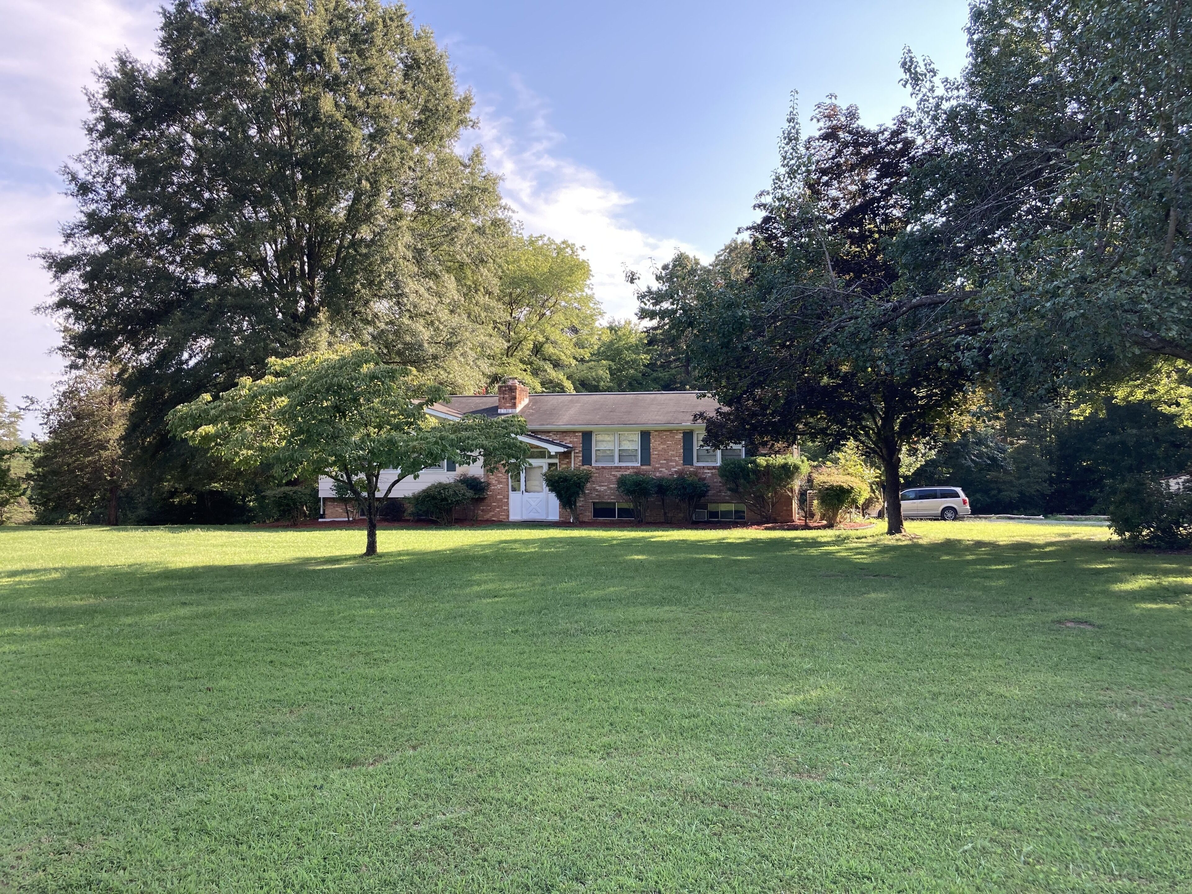 A residential house with a well-maintained lawn and large trees.