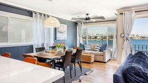 Un'area pranzo con un tavolo apparecchiato per due, un divano e vista sul porto turistico.