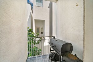 Enjoy al fresco dining on the balcony with a barbecue grill and a view of the surrounding building.