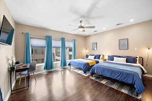 Relax in a spacious room with a large bed, desk, and natural light pouring in through the window.