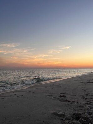 A beach with footprints in the sand and a calm sea.