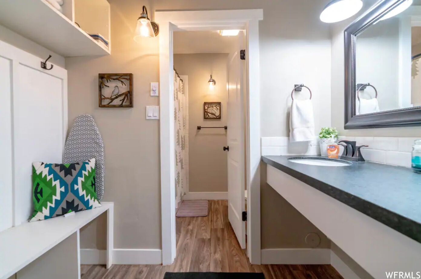 A modern bathroom with a vanity, a large mirror, and a shower area.