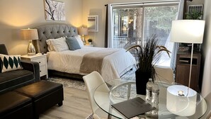 Ein modernes Schlafzimmer mit einem großen Bett, einem Glastisch und Blick ins Freie.