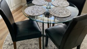A round glass table with four black chairs, a vase with flowers, and a view of a window with blinds. - Jo Mac Cottage- Quiet Home near UNC Chapel Hill (Chapel Hill)