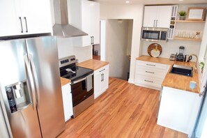 Enjoy cooking in this well-equipped kitchen with a refrigerator, oven, microwave, sink, and coffee machine.