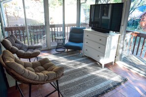 Relax in a space with a comfortable seating area, flat-screen TV, and large glass doors leading to a scenic view.