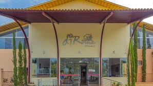 A building with a yellow roof, a covered entrance, and a sign with a logo. - DiRoma Fiori com um dia no Acqua park (Caldas Novas)