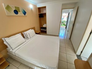 A hotel room with a bed, a wardrobe, a small table, and a wall-mounted light. - DiRoma Fiori com um dia no Acqua park (Caldas Novas)