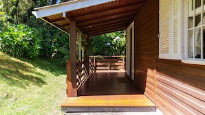 Eine hölzerne Veranda mit Holzgeländer, einer Tür und einem Fenster mit Fensterläden.