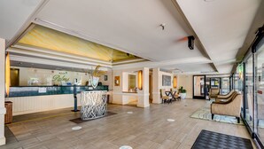 A hotel lobby with a reception desk, seating area, and a large window.
