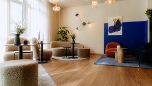 A modern living room with a sofa, armchairs, a coffee table, and a rug. There are pendant lights, a wall-mounted lamp, and a painting on the wall. - Moods Hotel Dortmund (Dortmund)