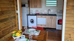 Eine kleine Küche mit Holzausstattung, einer Waschmaschine, einer Mikrowelle und einem kleinen Fenster.