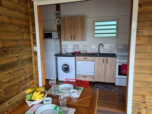 Une cuisine compacte avec des meubles en bois, un lave-linge, un four à micro-ondes et une petite fenêtre.