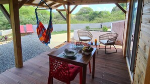 Eine Holzterrasse mit einem Tisch für Zwei, einer Hängematte und Korbstühlen.