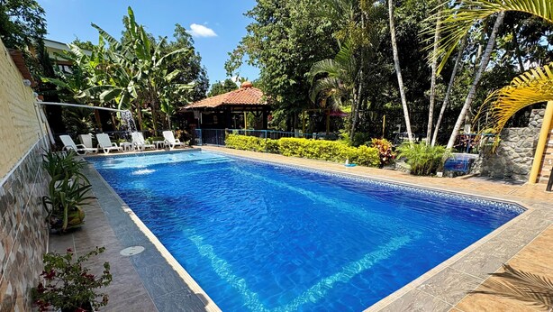 A rectangular swimming pool with a tiled edge, surrounded by a tiled deck, and adjacent to a building with a tiled roof. - Amazing and comfortable country house. Very close to the Rozo small town. (Palmira Rozo)