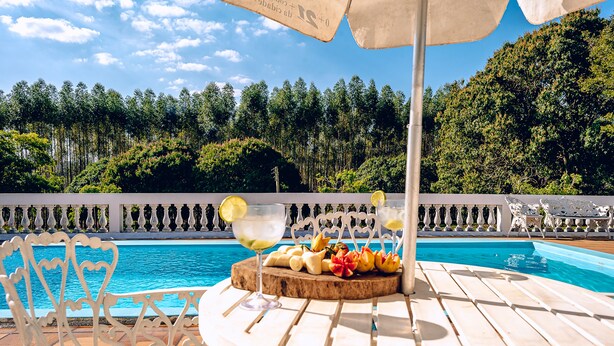 Escena junto a la piscina con una mesa, sillas y una bandeja de frutas.