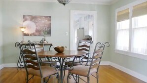 Comedor con una mesa redonda y cuatro sillas, una araña y un cuadro en la pared.