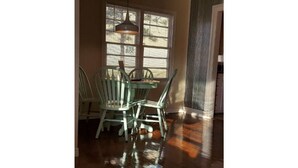 A dining area with a table and chairs, a hanging light fixture, and a window with blinds. - Rambler *pet friendly* garage private deck (Amarillo)