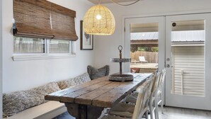 Un coin repas rustique avec une table en bois, des bancs en osier et un luminaire suspendu.