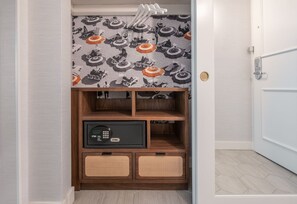 A hallway with a patterned wallpaper, a wooden cabinet with drawers, and a door.