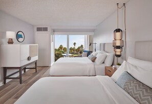 A hotel room with two beds, a desk, a lamp, and a view of palm trees. - The Pierside (Santa Monica)