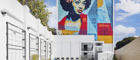 A pool area with lounge chairs, a mural, and a 'Welcome' sign.