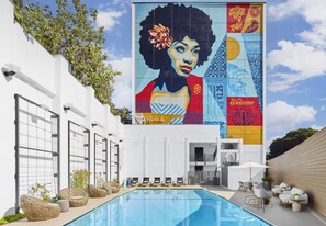 A pool area with lounge chairs, a mural, and a 'Welcome' sign.
