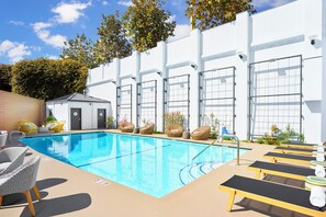 A swimming pool with lounge chairs and a small building, likely a changing room or storage. - The Pierside (Santa Monica)